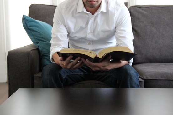 man on couch reading bible 596434